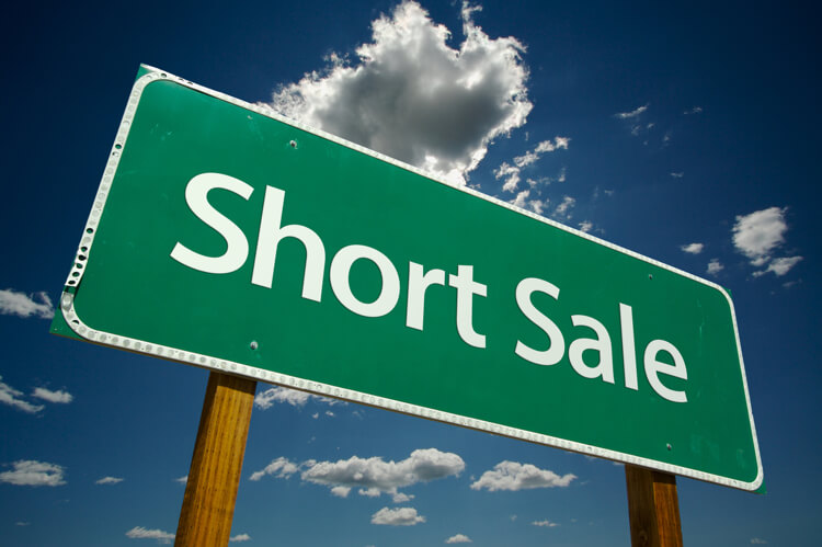 Short Sale Green Road Sign on Dramatic Blue Sky with Clouds.